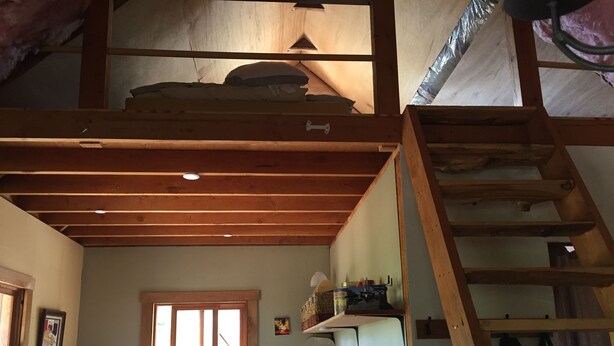 A rustic kitchen with wooden beams, a stove, and a window. - Cozy Cabin on a small Off Grid Homestead (Shawnigan Lake)