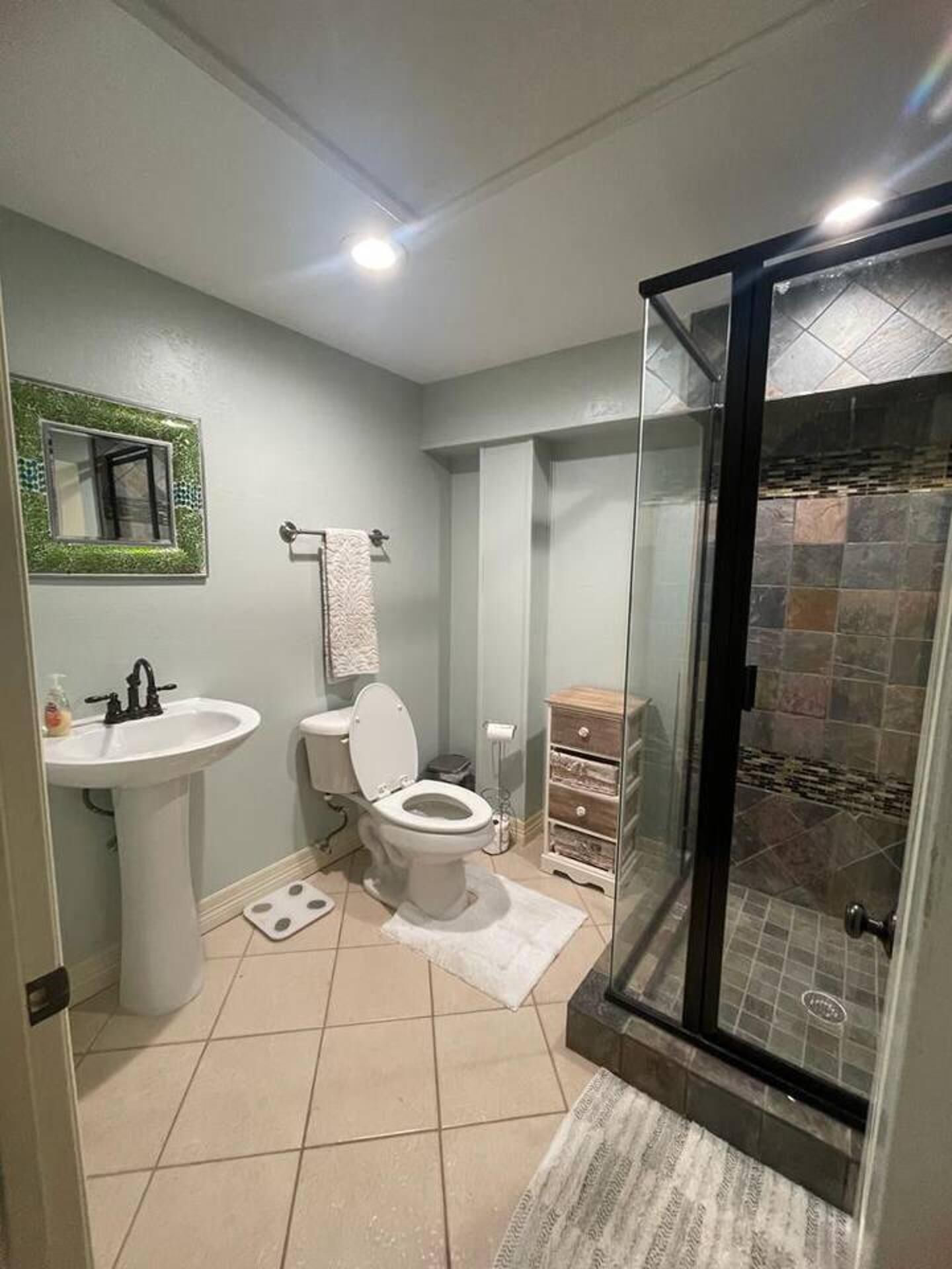 A bathroom with a sink, toilet, and shower area.
