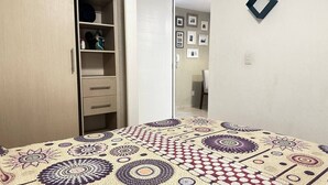 Ein Schlafzimmer mit Bett, Kleiderschrank und einer Tür zu einem anderen Raum.