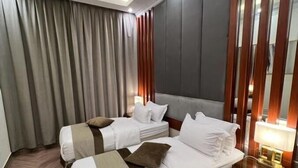 A hotel room with two beds, a large mirror, and a nightstand with a lamp. - Smayah Hotel (Riyadh)