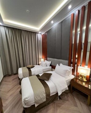 Ein Hotelzimmer mit zwei Betten, einem großen Spiegel und einem Nachttisch mit Lampe.