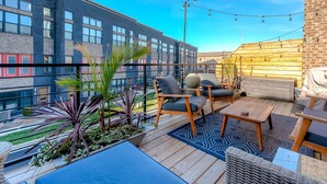 En takterrass med utomhusmöbler, utsikt över en modern byggnad och ljusslingor.