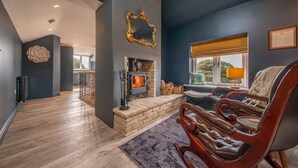 A modern living room with a stone fireplace, leather armchairs, and a large mirror on the wall. - May Cottage Titchwell, Norfolk (Titchwell)