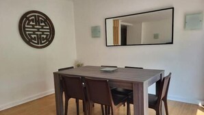 A dining area with a rectangular table, six chairs, a decorative wall piece, and a large mirror. - Superbe Appartement , Lumineux, Proche Paris (Montrouge)