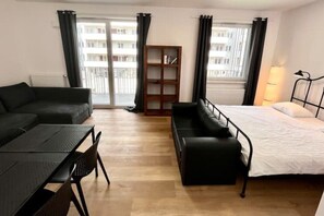Relax in this stylish room with a single bed, black sofa, and wooden bookshelf.