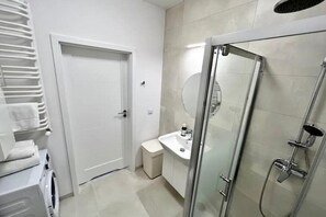 Bathroom features a glass-enclosed shower, sink, and mirror.