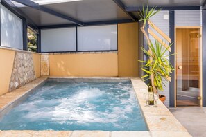 Ett spaområde med ett bubbelbad, stenmurar och en trädörr.