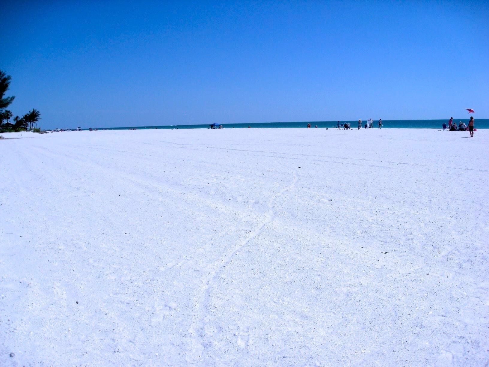 Una spiaggia con cielo sereno e alcune persone in lontananza.