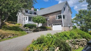 Une maison à deux étages, avec des fondations en pierre, un garage et un jardin bien entretenu.