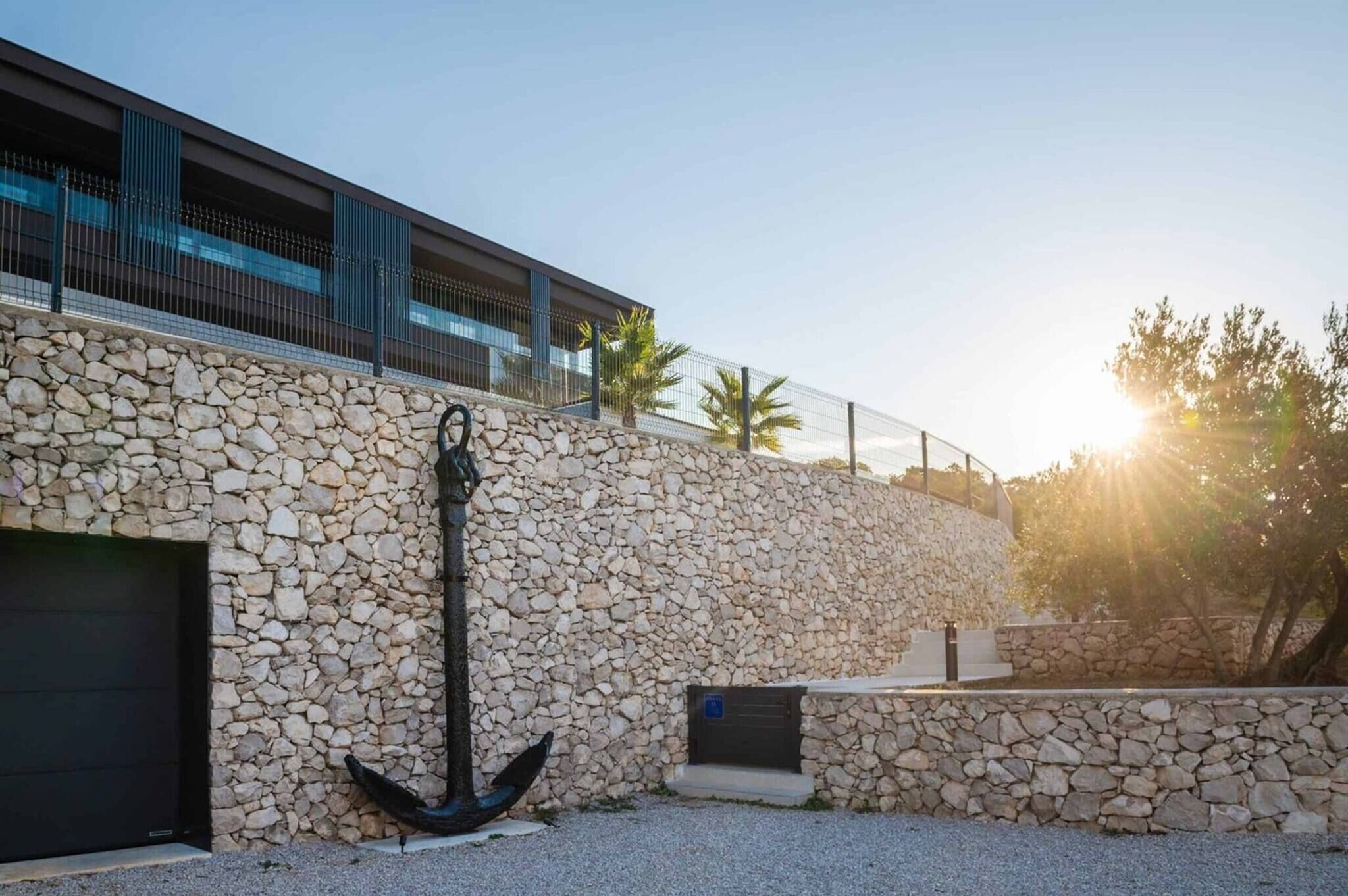 A modern building with a stone facade, a large anchor sculpture, and a garage door.
