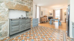 A kitchen with a stone wall, a built-in stove, and a patterned floor. - Rheithordy -  a self catering cottage that sleeps 9 guests in 5 bedrooms (Blaenau Ffestiniog)