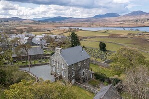 A stone house with a courtyard, surrounded by a rural landscape with fields and a lake. - Rheithordy -  a self catering cottage that sleeps 9 guests in 5 bedrooms (Blaenau Ffestiniog)