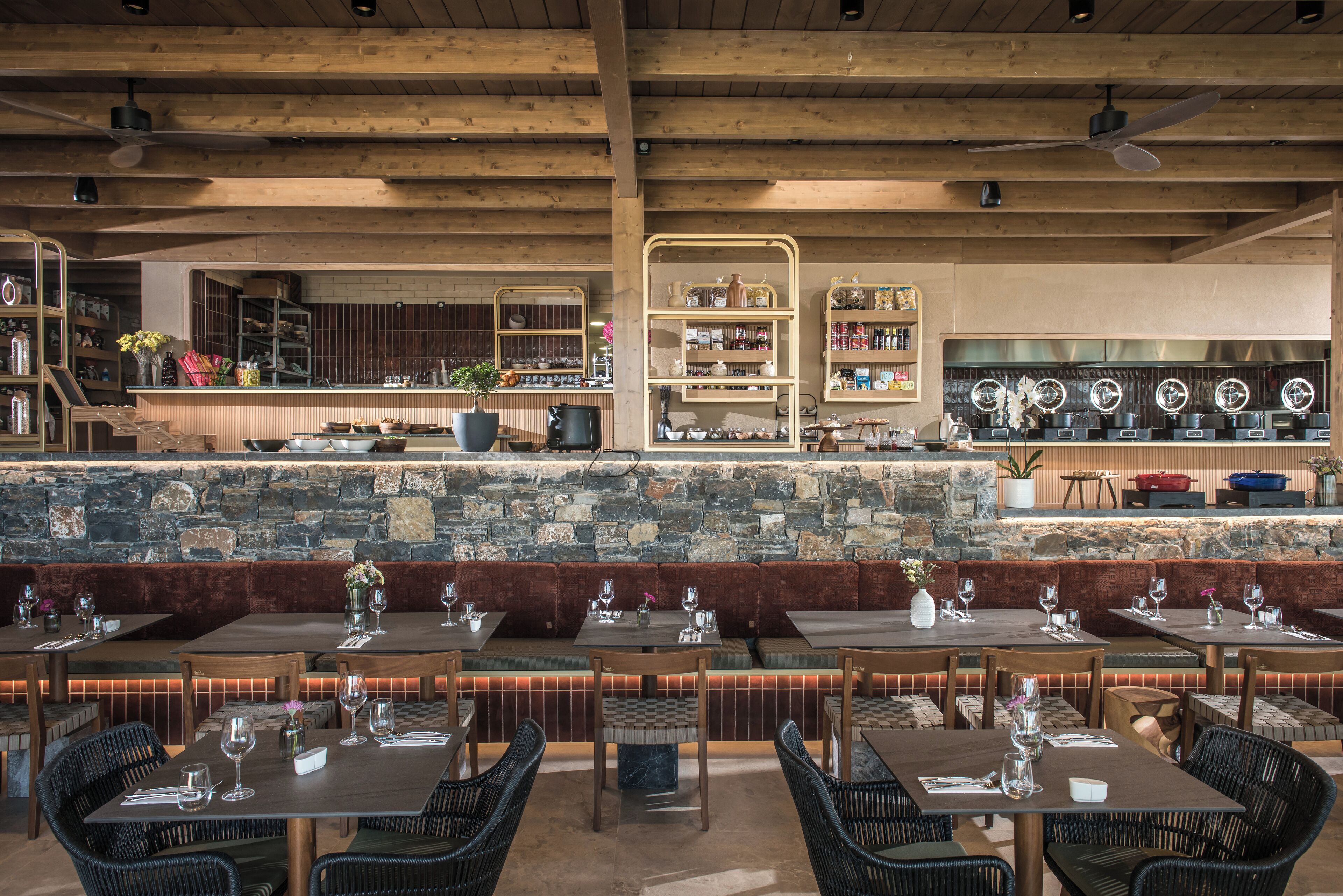 A restaurant with a stone bar, wooden ceiling, and wicker furniture.