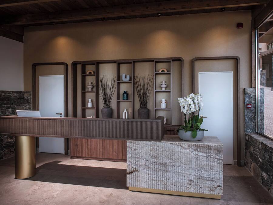 A reception desk with a modern design, a stone wall, and a view of the outdoor area.