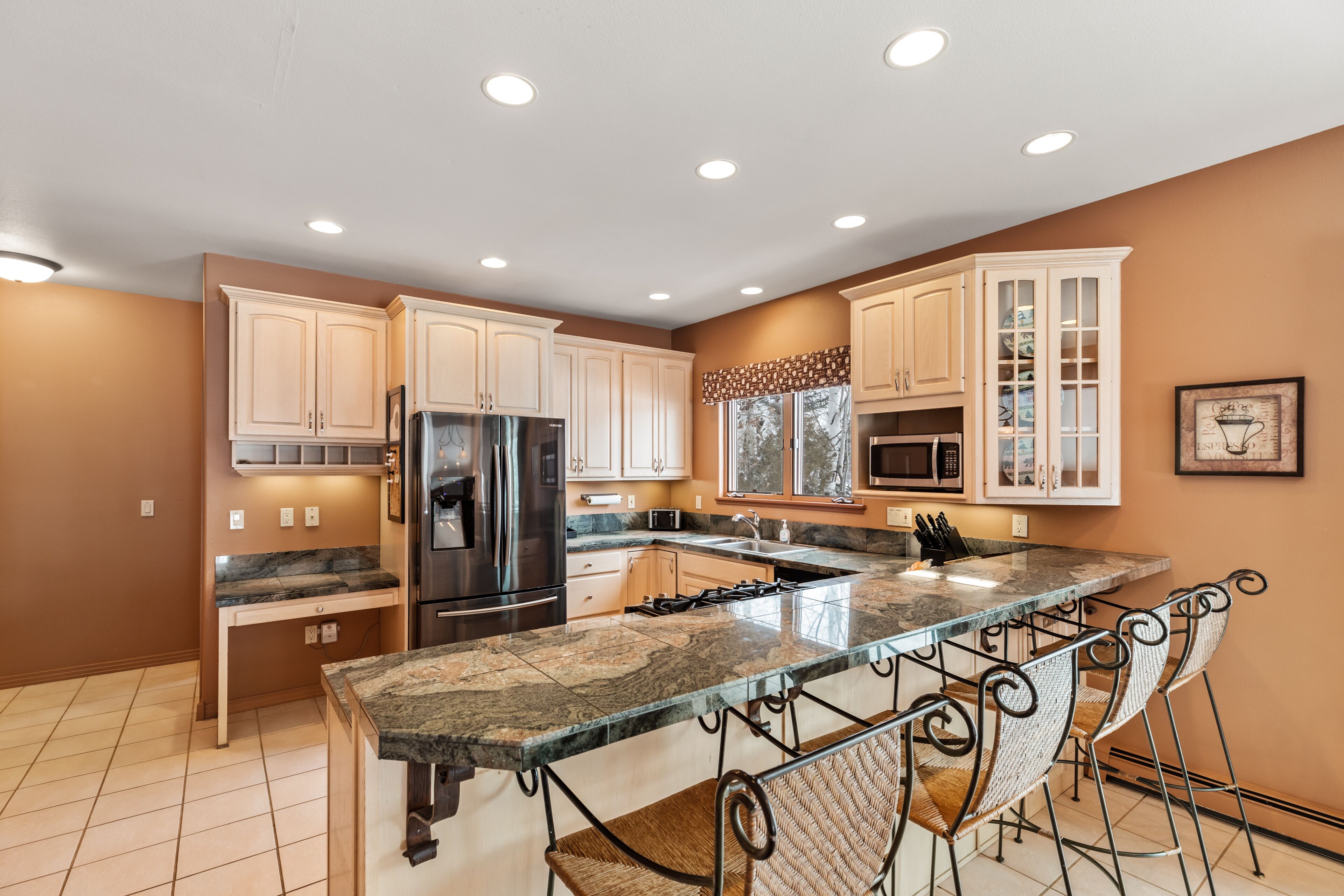 A modern kitchen with a central island, stainless steel appliances, and a bar seating area.