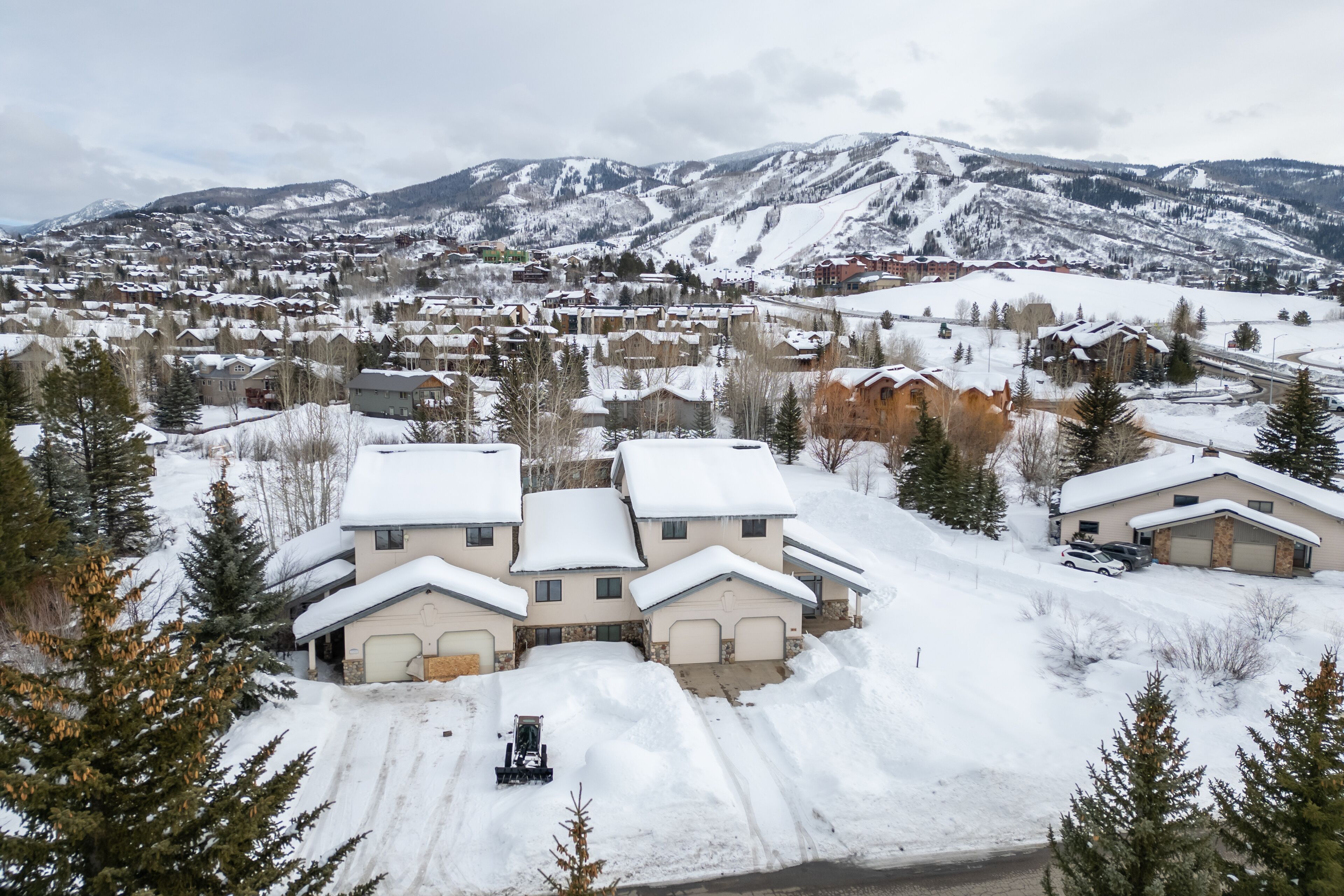 A residential area with snow-covered houses and a mountainous backdrop.