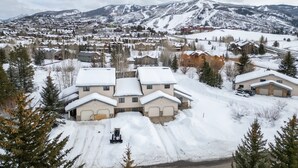 Un quartier résidentiel avec des maisons enneigées et une chaîne de montagnes en arrière-plan.