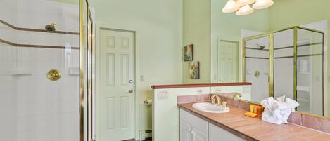 A bathroom with a shower, sink, and vanity.