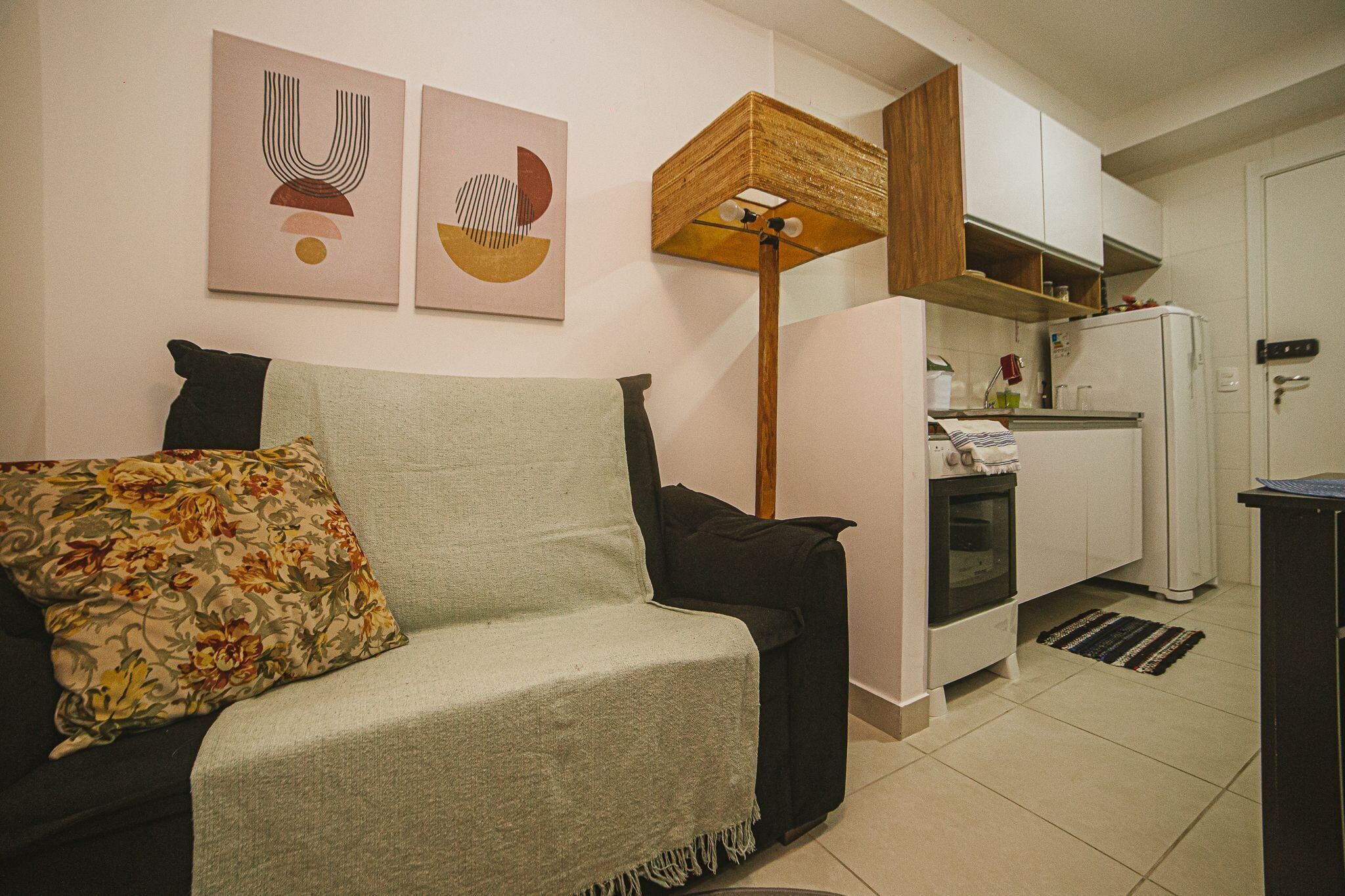 A living room with a sofa, a coffee table, and a kitchen area with a refrigerator and oven.