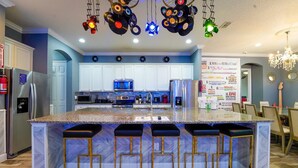 Una cocina moderna con una isla central, taburetes de bar y una lámpara de techo original.