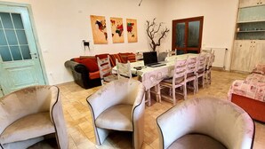 A living room with a dining table, chairs, a sofa, a TV, and a bookshelf. - 4½-room apartment (126m²) on ground floor with veranda and access to the garden. (Sardegna)