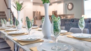 A dining area with a long table set for a meal, featuring clear glassware and green decorative elements. - Last Minute Disney! Private Pool, Hot Tub & Themed Bedrooms. Book Now! #105265 (Orlando)