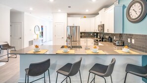 A modern kitchen with a central island, bar stools, and a clock on the wall. - Last Minute Disney! Private Pool, Hot Tub & Themed Bedrooms. Book Now! #105265 (Orlando)