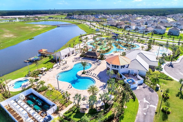 A resort with a large swimming pool, a dock, and a residential area with houses.