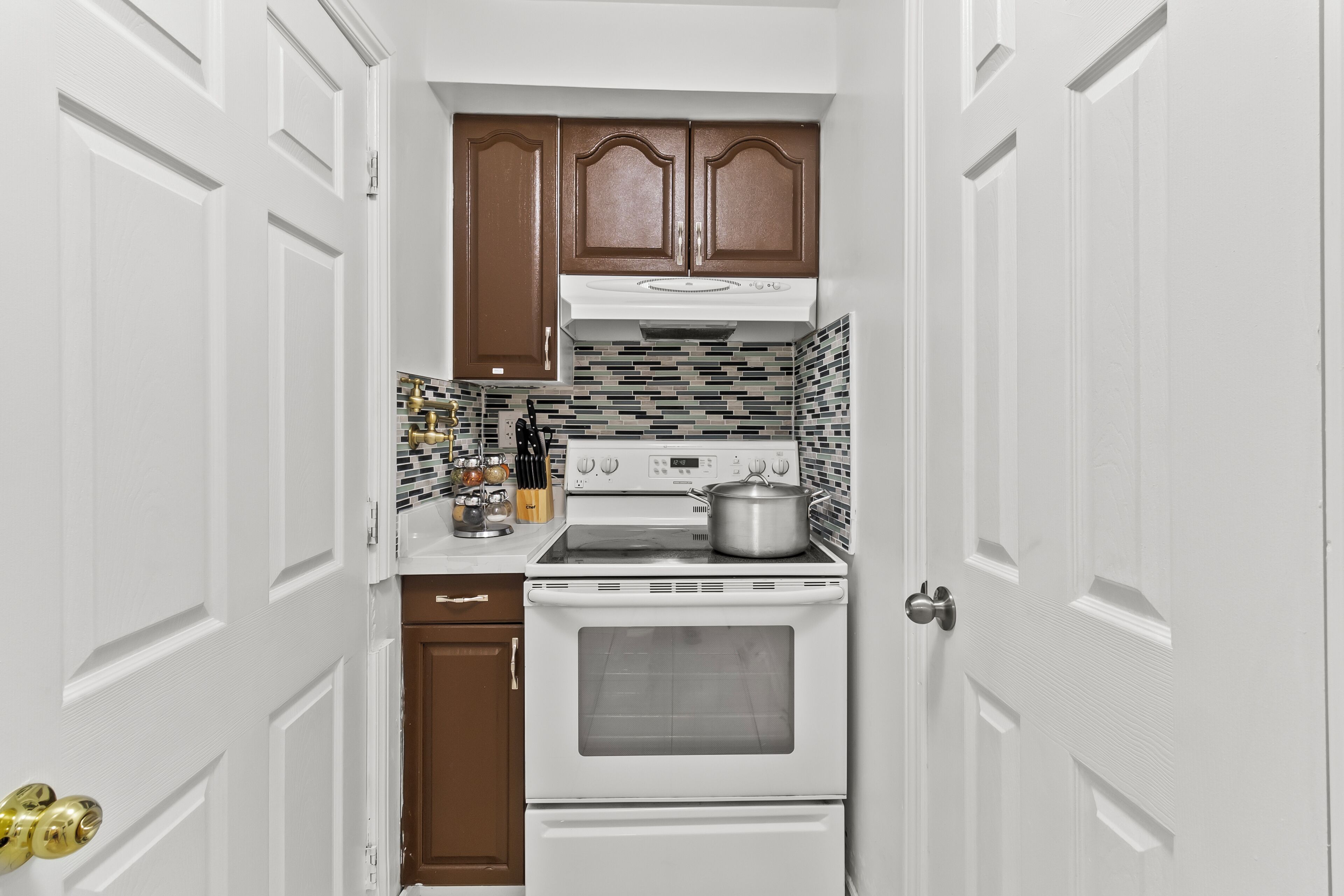 A compact kitchen with white cabinetry, a stove, and a microwave.