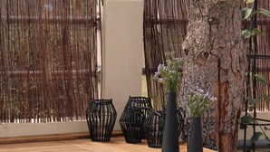 A swimming pool with a wooden deck, surrounded by a bamboo fence and a tree. - Asteria Apartments (Hersonissos)