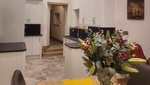 Una cocina estrecha con armarios blancos y techo de madera.
