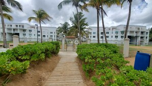 A pathway leading to a gated entrance with a white building in the background. - Amazing beachfront apartment on the beach (Río Grande)