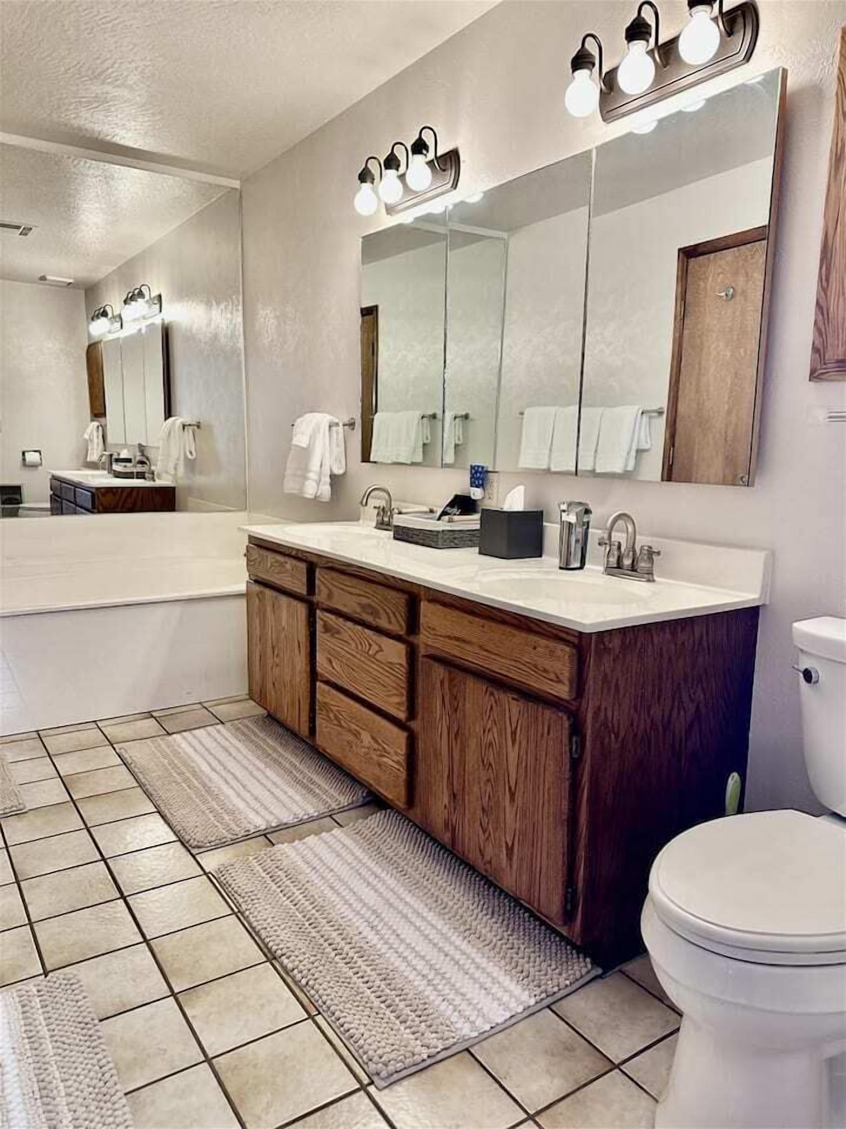 Ein modernes Badezimmer mit einem großen Spiegel, einem Holzwaschtisch und einer weißen Toilette.