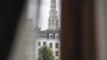 Blick auf ein Kathedrale mit einem hohen Turm, umgeben von Gebäuden und einem Baum im Vordergrund.