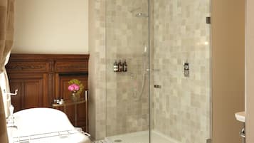A modern bathroom with a glass-enclosed shower, a freestanding bathtub, and a vanity with a mirror and toiletries.