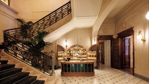 A grand lobby with a marble floor, a central bar area, and a staircase with ornate railings. - Hotel Fleur de Ville (Brussels)