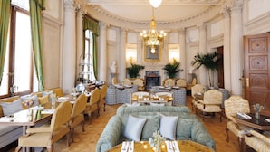 A grand room with a large sofa, dining tables, and chairs, featuring classic architecture and elegant decor. - Hotel Fleur de Ville (Brussels)