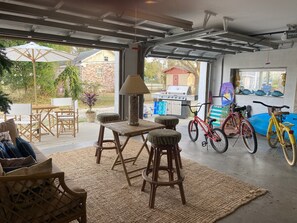 Eine Garage mit Essbereich, Grill, Fahrrädern und Blick auf die Nachbarschaft.