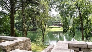 Un parque tranquilo con un estanque, bancos de piedra y abundante vegetación.