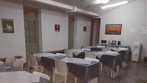 A conference room with tables and chairs, a door, and a painting on the wall. - HOSTAL AMALAYA (Salta)