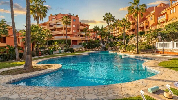 A swimming pool surrounded by palm trees and a building with balconies. - Reserva De Marbella apt by Costarentals - Ref M43 (Artola)
