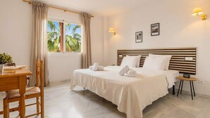 A hotel room with a bed, a desk, a chair, a small table, and a window with curtains. - Reserva De Marbella apt by Costarentals - Ref M43 (Artola)