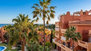 A resort with multiple-story buildings, a swimming pool, and palm trees. - Reserva De Marbella apt by Costarentals - Ref M43 (Artola)