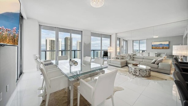 Ein modernes Wohnzimmer mit einem Glastisch, weißen Sofas und Blick auf die Stadt.