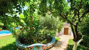 A garden area with a mosaic-tiled planter, a pool, and a pathway leading to a building.