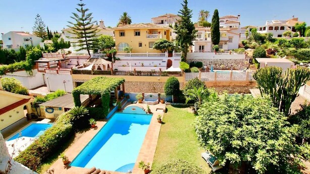 A residential area with a swimming pool surrounded by greenery and houses.