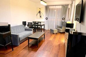 Relax in this stylish living room with a comfortable sofa, dining table, and flat-screen TV.