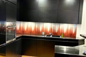 Enjoy cooking in this well-equipped kitchen with a stainless steel oven, sink, and stylish backsplash.