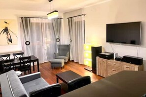 Relax in this stylish living room with a flat-screen TV, dining area, and comfortable seating for two.