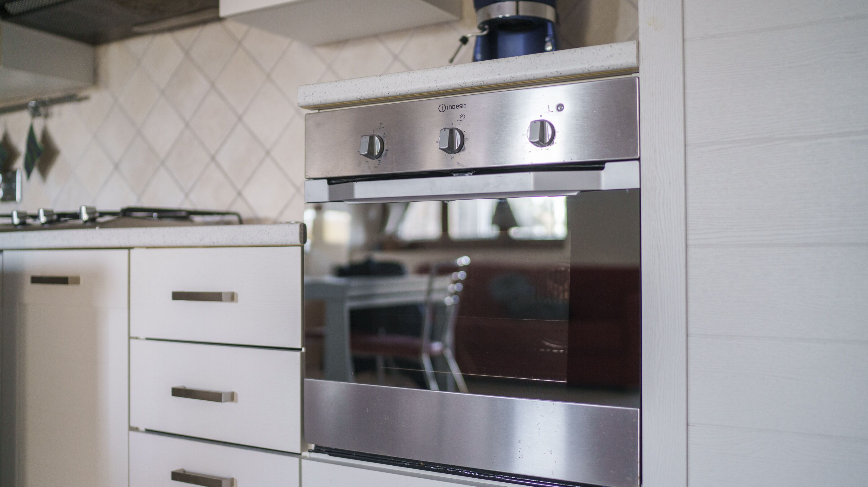 A stainless steel oven with four knobs, a control panel, and a glass window.